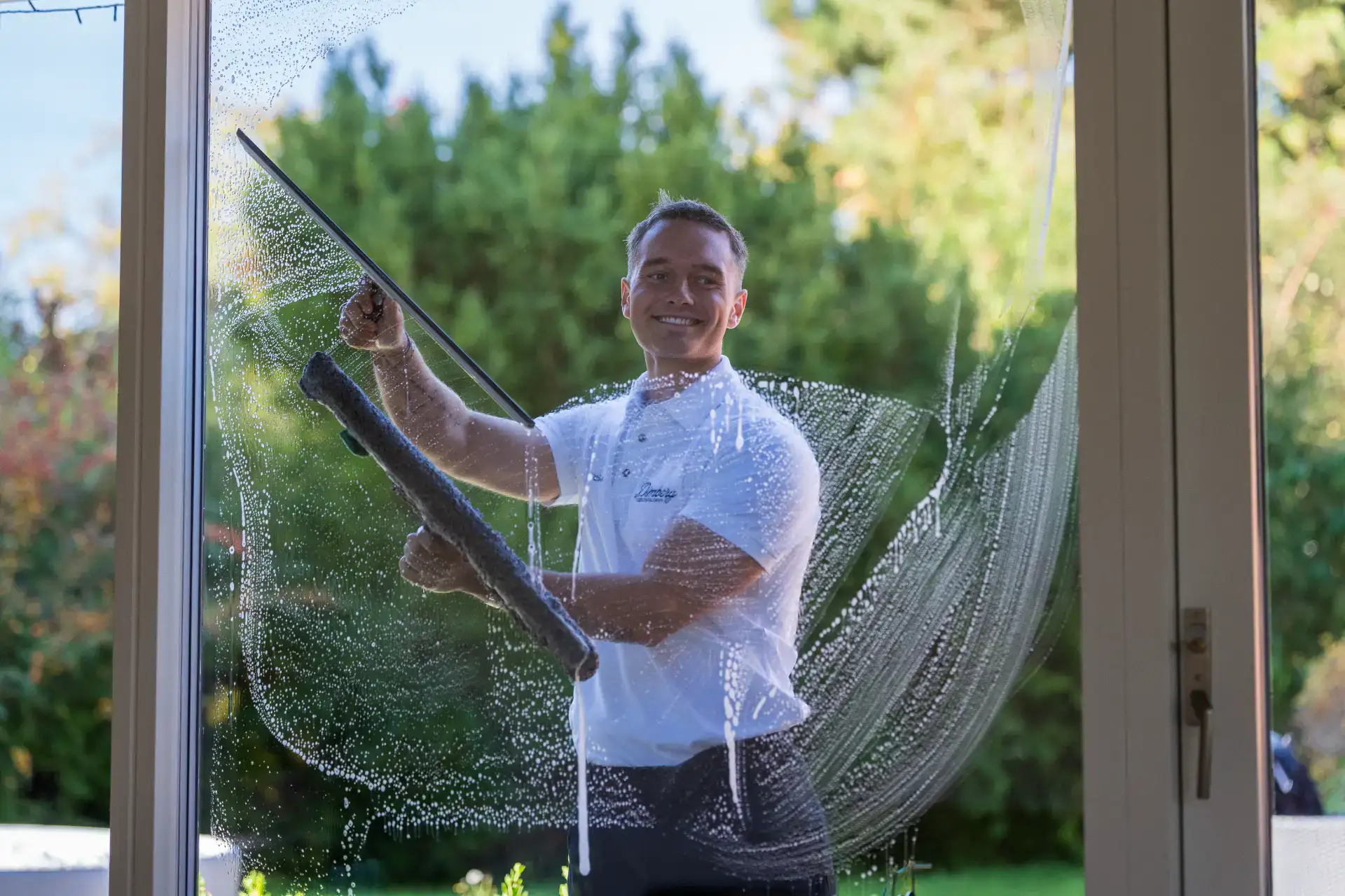 Vinduespudser rengør vindue med skum og værktøj.